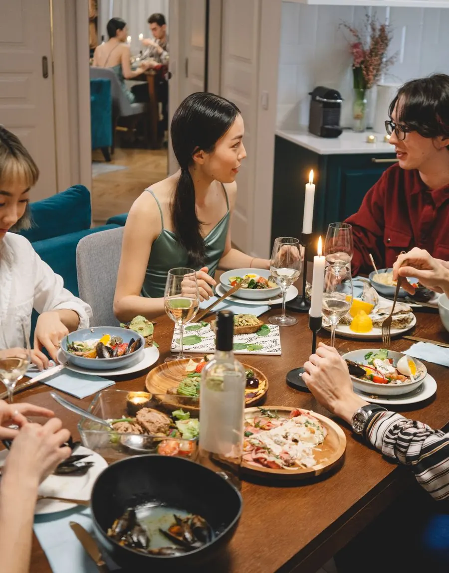 Friends talking over a candlelit dinner table covered in shared dishes